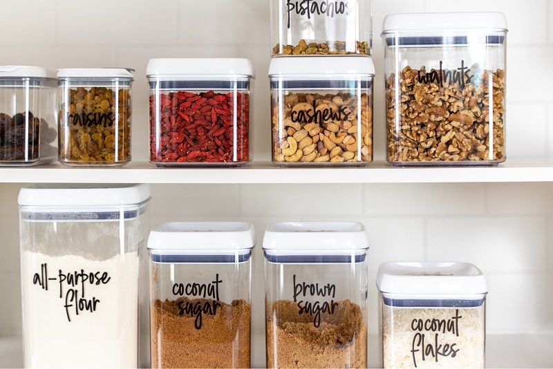 Labeled clear staple food containers in kitchen pantry