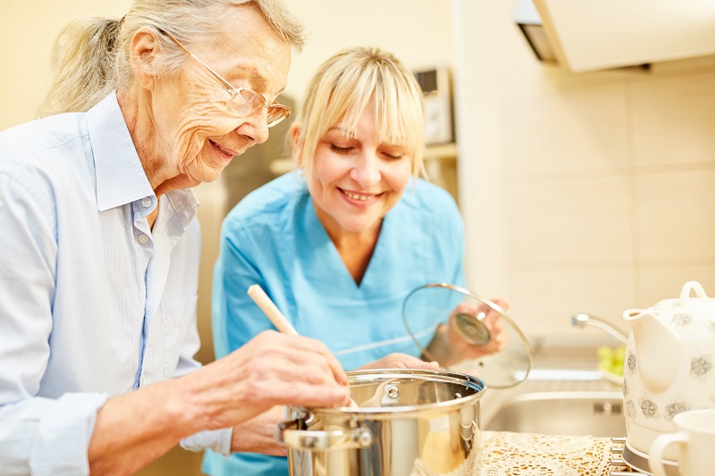 Elderly mother and adult daughter enjoy preparing a meal in the kitchen