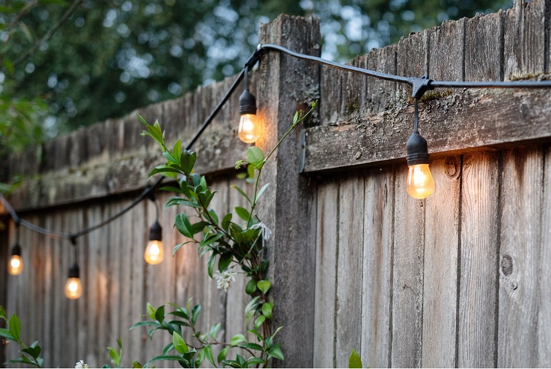 Outdoor wooden fence with light strings during summertime evening