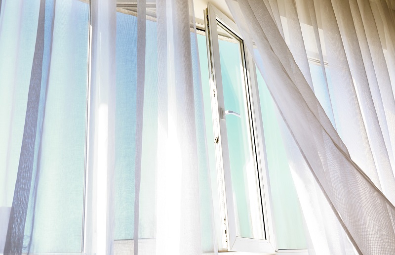 Sunny open window with drapes blowing from a breeze