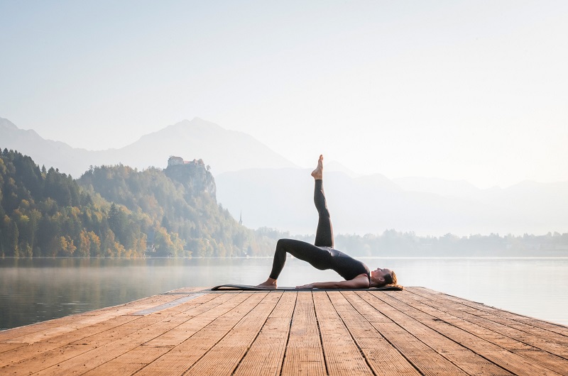 Woman doing yoga on lake pier 
