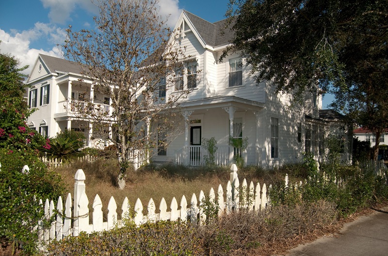 Abandoned white two-story house with unkempt lawn