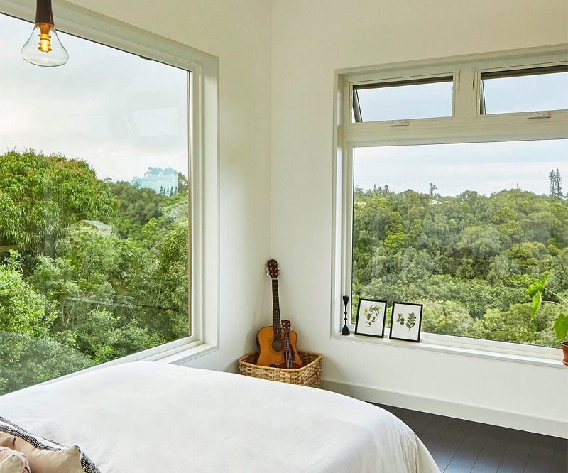 Two large picture windows and two awning windows by Andersen Windows with views of a forest 