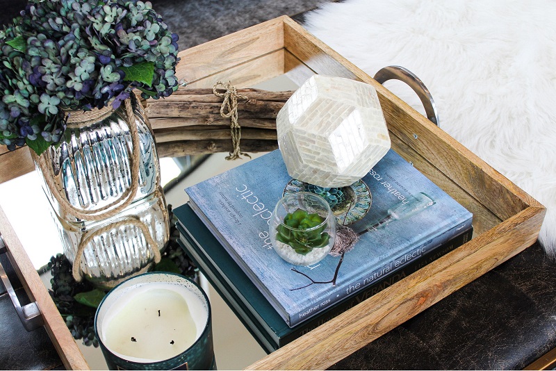 Decorative ottoman coffee table with tray, accent books, candles and flowers
