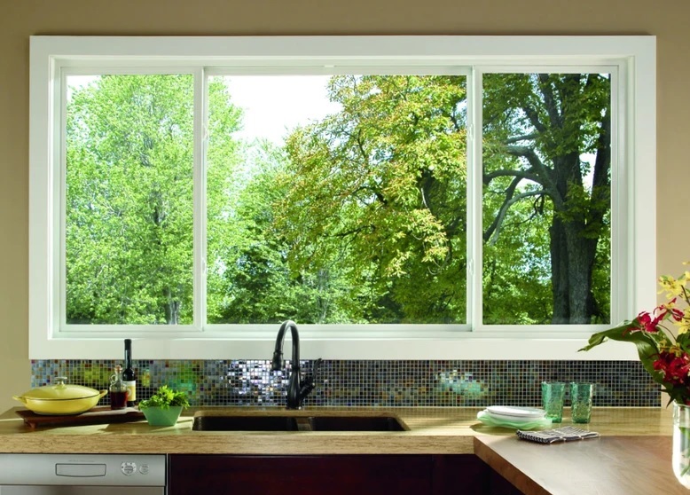 Pella sliding windows in kitchen above sink with views of trees