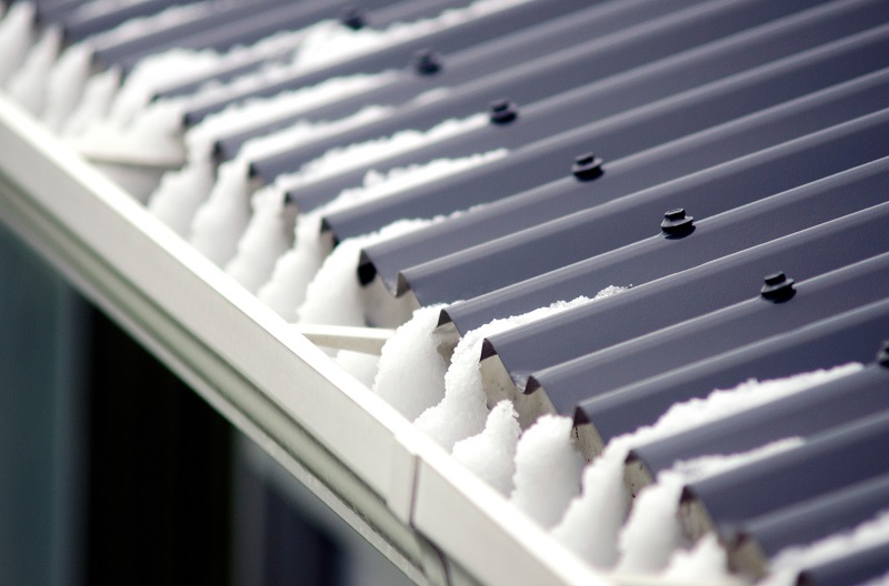 Closeup view of metal roof and gutter with ice and snow