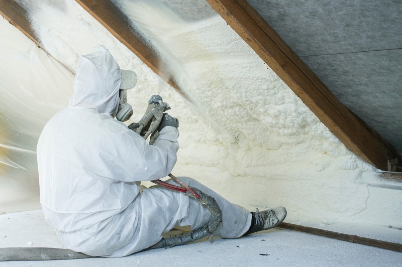 Contractor installing spray foam insulation in an attic