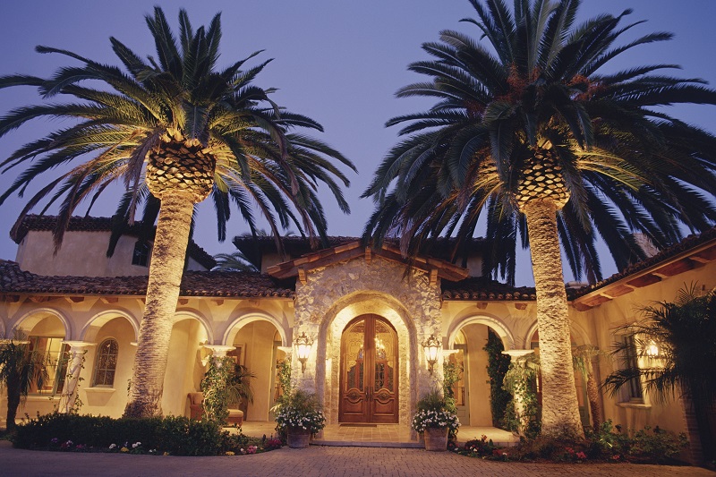 Luxury Mediterranean home with arches highlighted with outdoor lighting
