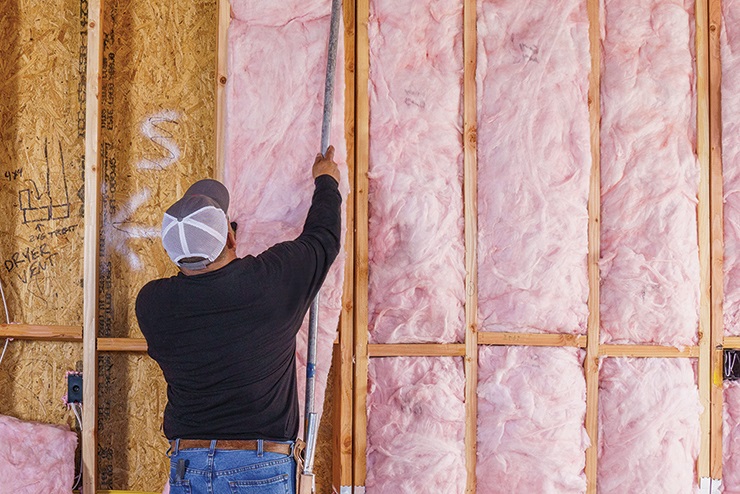 Contractor installing Owens Corning fiberglass insulation