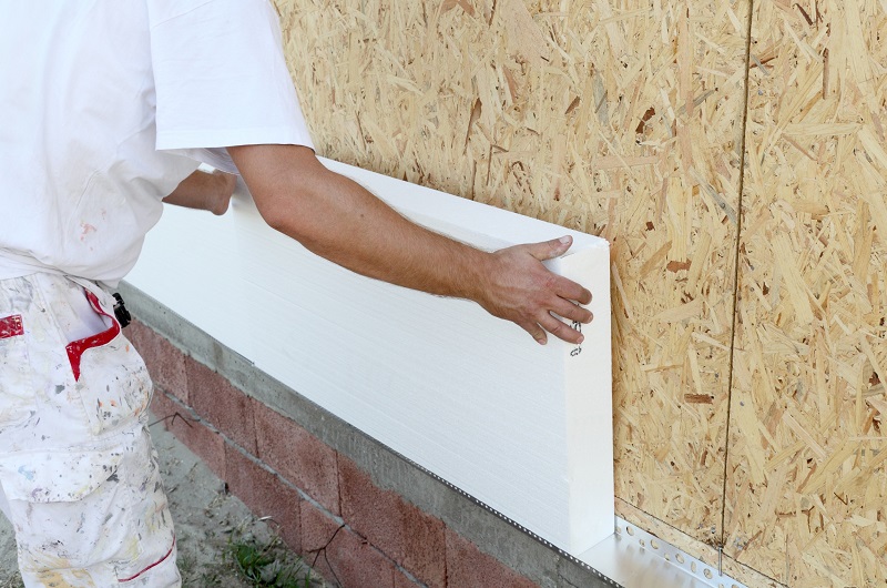Rigid foam board insulation being installed on the exterior of a house