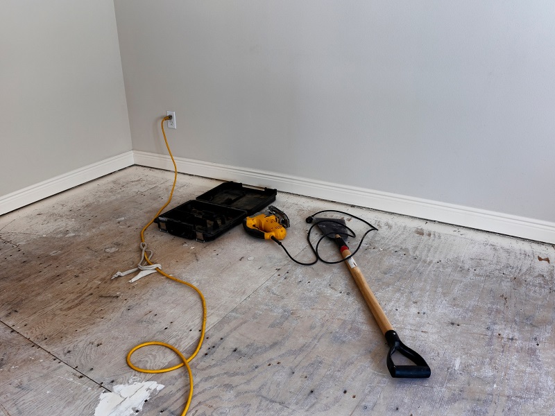 Empty room with exposed plywood flooring and tools
