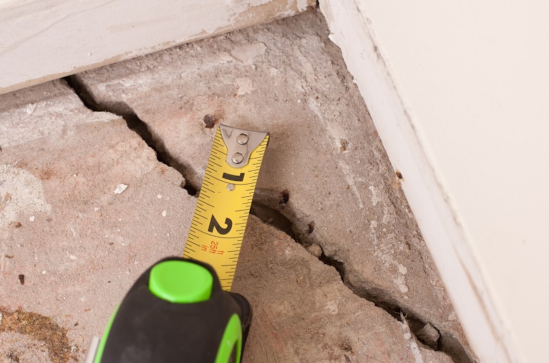 Crack in house foundation concrete with tape measure