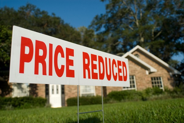 Priced reduced real estate sign on front lawn of home for sale
