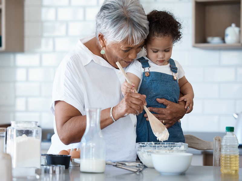 Grandmother smiling with young grandchild baking in the kitchen