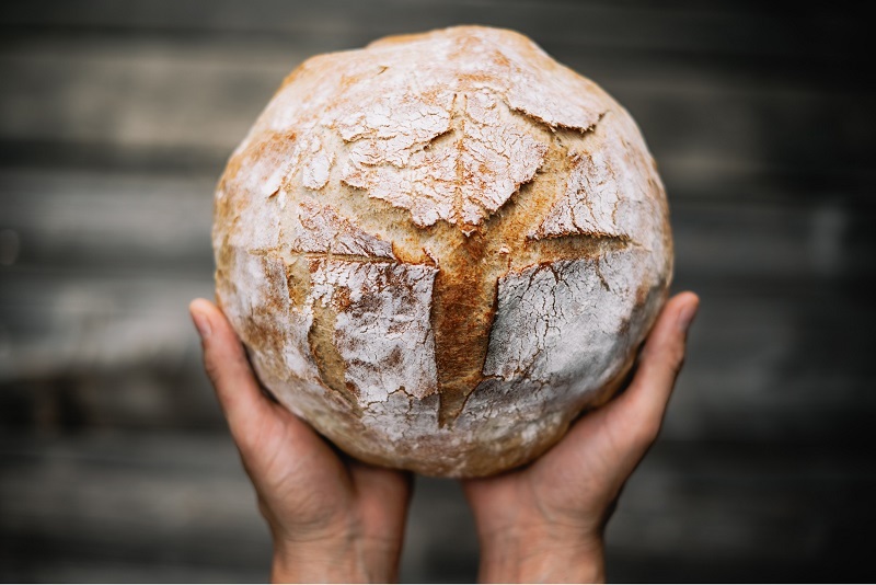 Hands holding a freshly baked loaf of bread