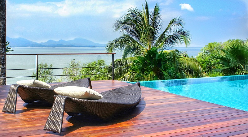 Vanishing edge infinity pool with deck, chaise lounge chairs and ocean and mountain views