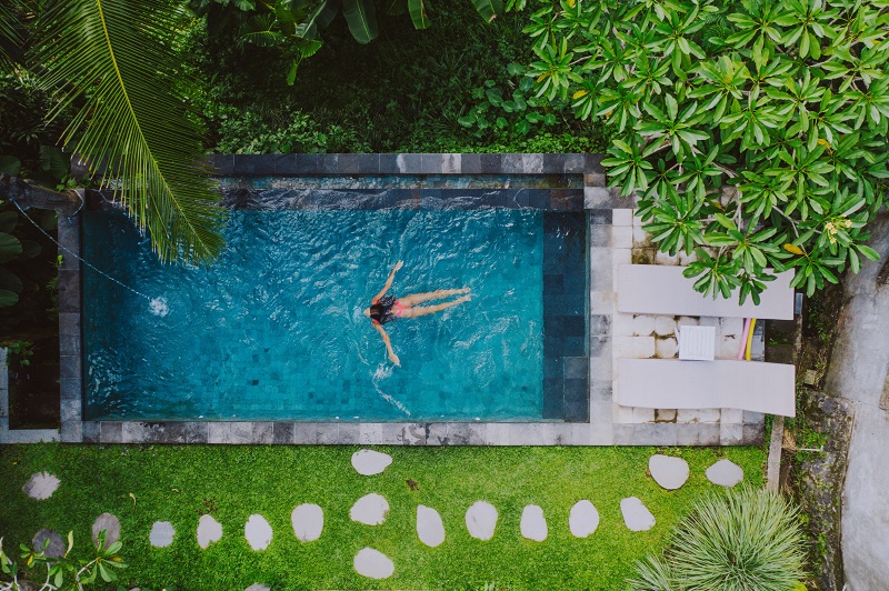 Woman swimming in a small saltwater pool in backyard