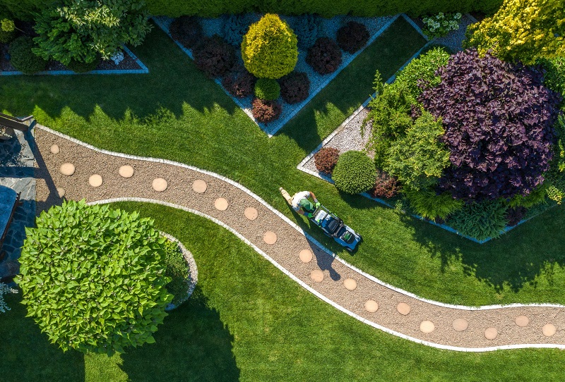 Aerial view of a well-manicured backyard with landscaper mowing grass