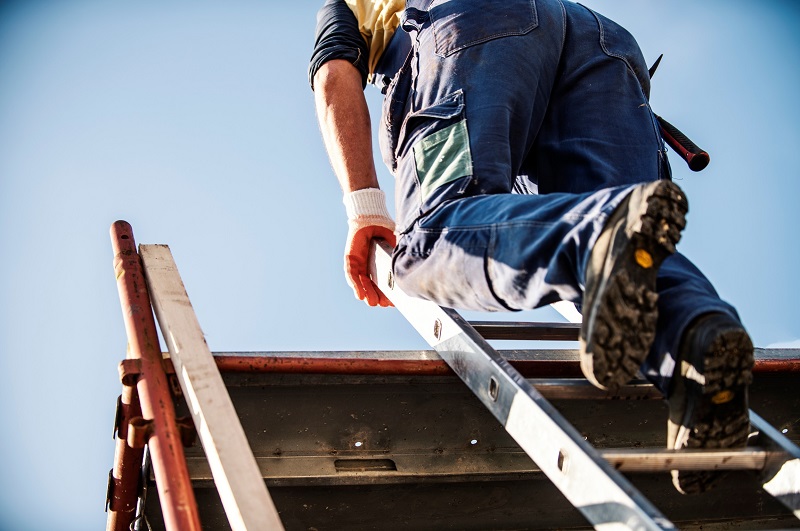 Residential roofer scaling ladder onto roof