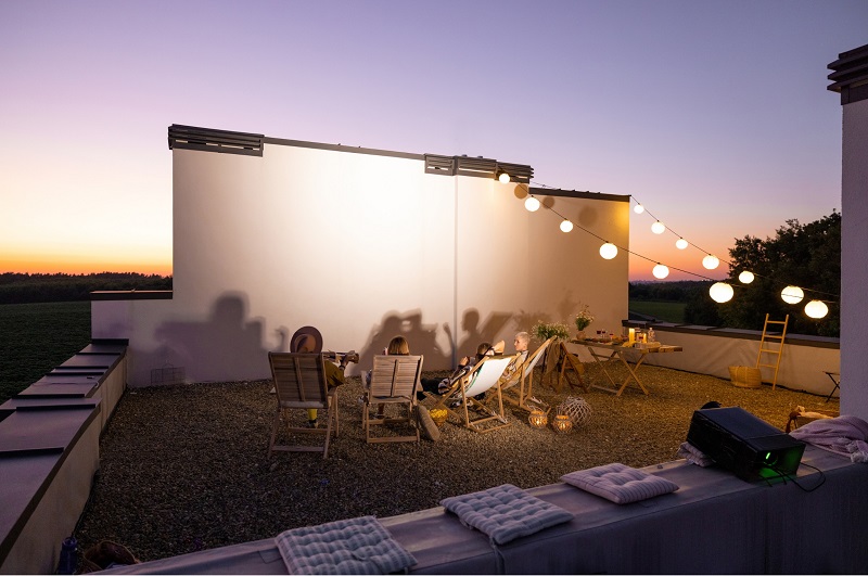 Young adults setting on a rooftop at a self-made projector theater