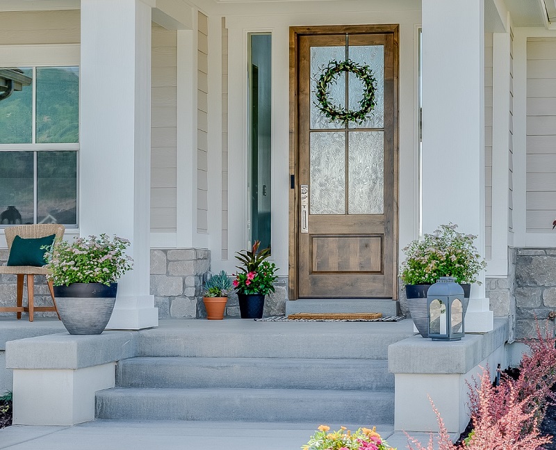 New farmhouse home with potted plants on front porch with curb appeal