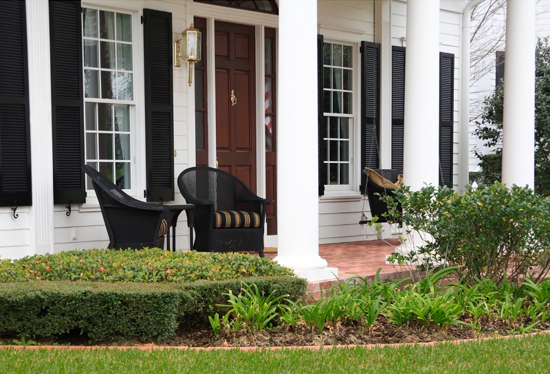 Traditional outdoor furniture on front porch of white colonial home