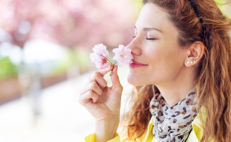 Woman enjoying the scent of a pink flower