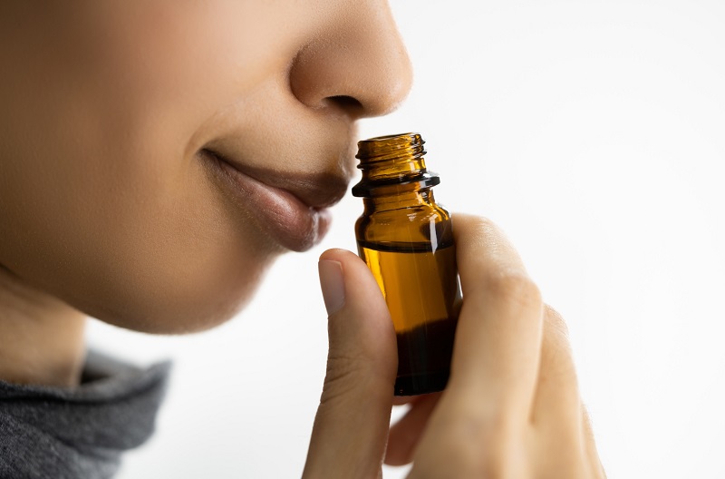 Woman going through Scent Retraining Therapy (SRT) smelling essential oils in bottle