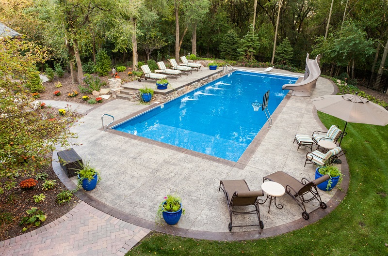 Backyard swimming pool surrounded by trees and grass
