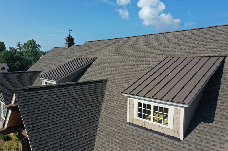 Close up view of a house roof with asphalt shingles and metal roofing