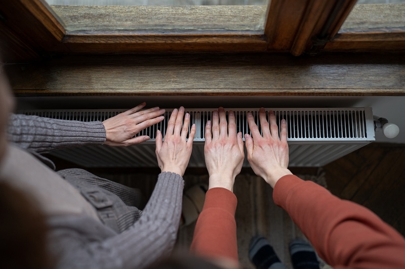 Cold temperatures indoors with hands over radiator