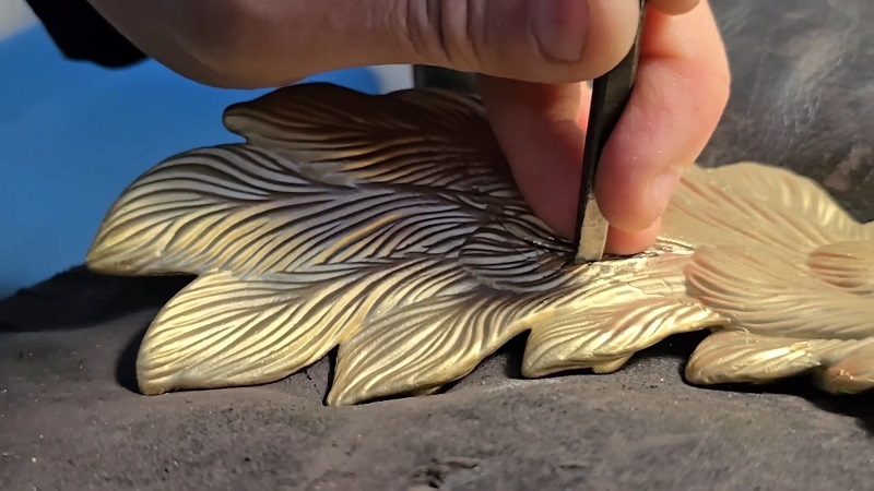 HF Home Jewels artisan at work, sharpening edges and lines with chisel of their Peacock clock