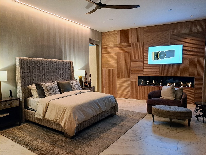 TNAH 2025 Elegant Warm Interior Design by Stephanie Osborn - Primary Bedroom Suite with wall cladding, ceiling fan, and fireplace