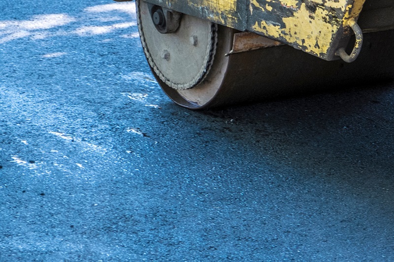 Asphalt paving machine rolling over repaired driveway