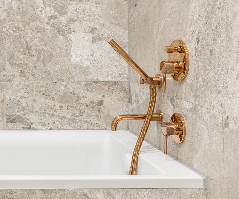 Bathtub with copper tub filler, knobs and hand shower