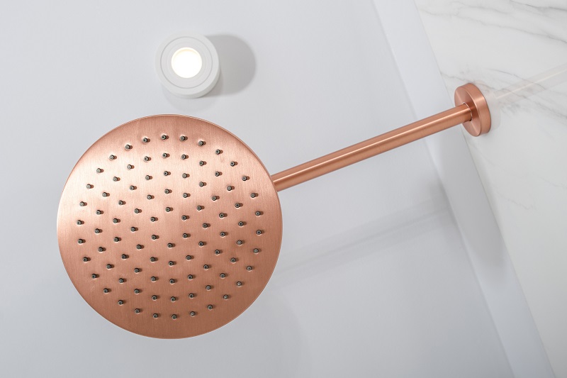 Copper showerhead in neutral white bathroom
