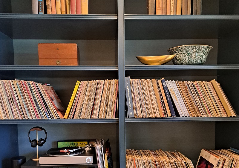 PSH 2025 Great Room designed by Rachel Duarte: Close-up view of the LP collection and warm shelving of the Great Room, which was painted in Dunn-Edwards Color of the Century: Viridian Odyssey (DE1925)