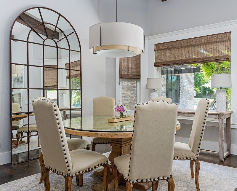 Round dining table next to large arched mirror in small dining room