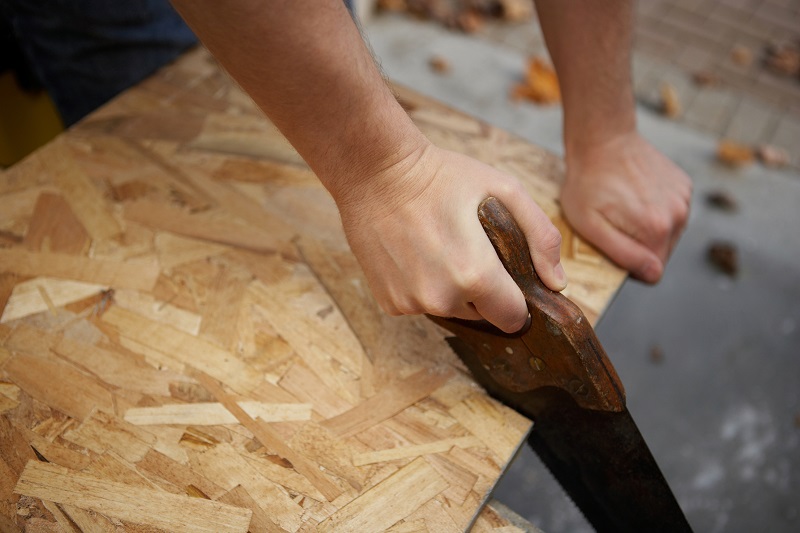 Trusty old handsaw being used to cut plywood