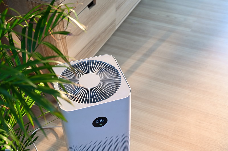 Air purifier on wooden floor next to indoor plant