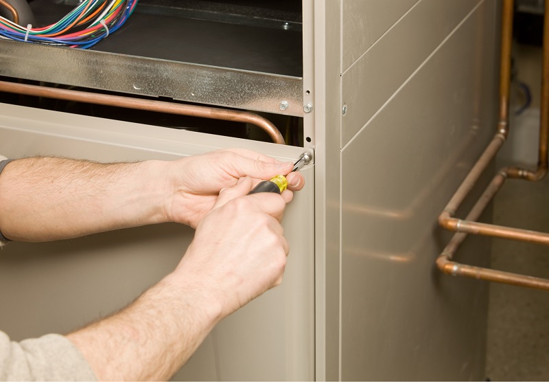 HVAC repair technician removing a furnace service panel
