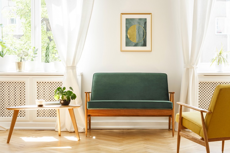 Bright mid-century living room with teal sofa, green chair and matching period painting