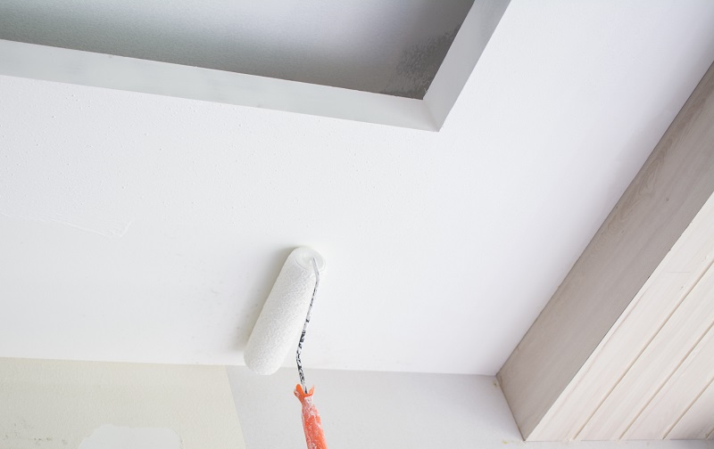 Painting a white gypsum plaster ceiling with paint roller