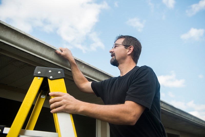 Homeowner checking roof shingles during the summer