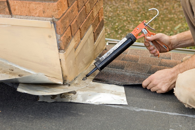 Contractor repairing flashing around a home's chimney 