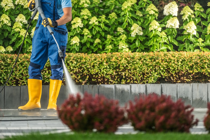 Paver driveway being power washed, while wearing proper protective gear