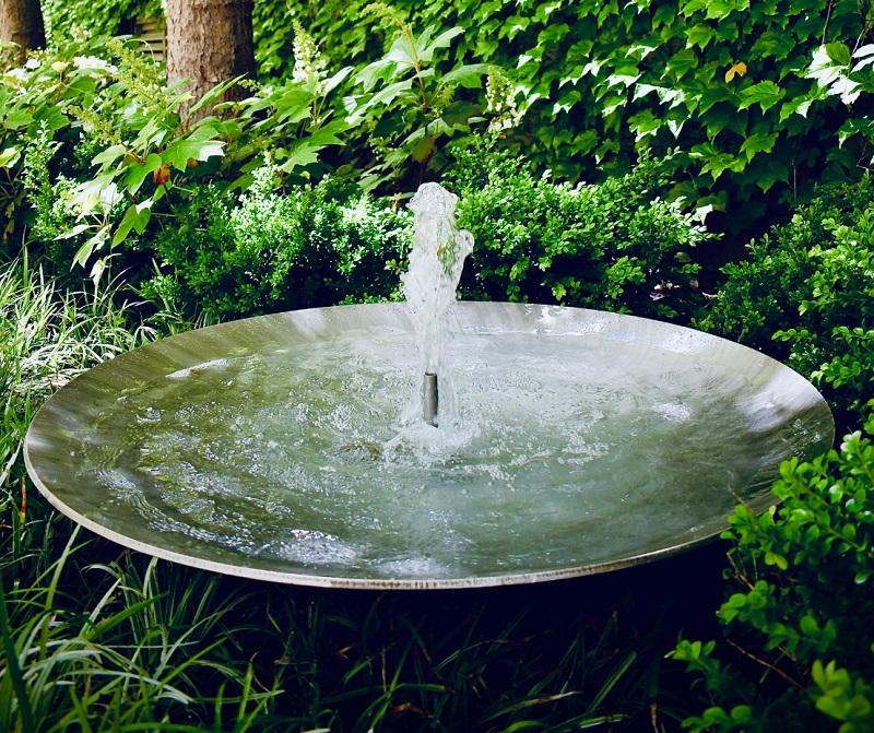 Peaceful outdoor water fountain surrounded by greenery