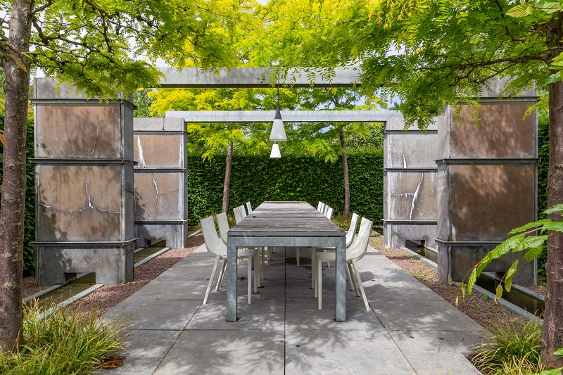 Private outdoor dining table surrounded by peaceful foliage and elegant hardscape