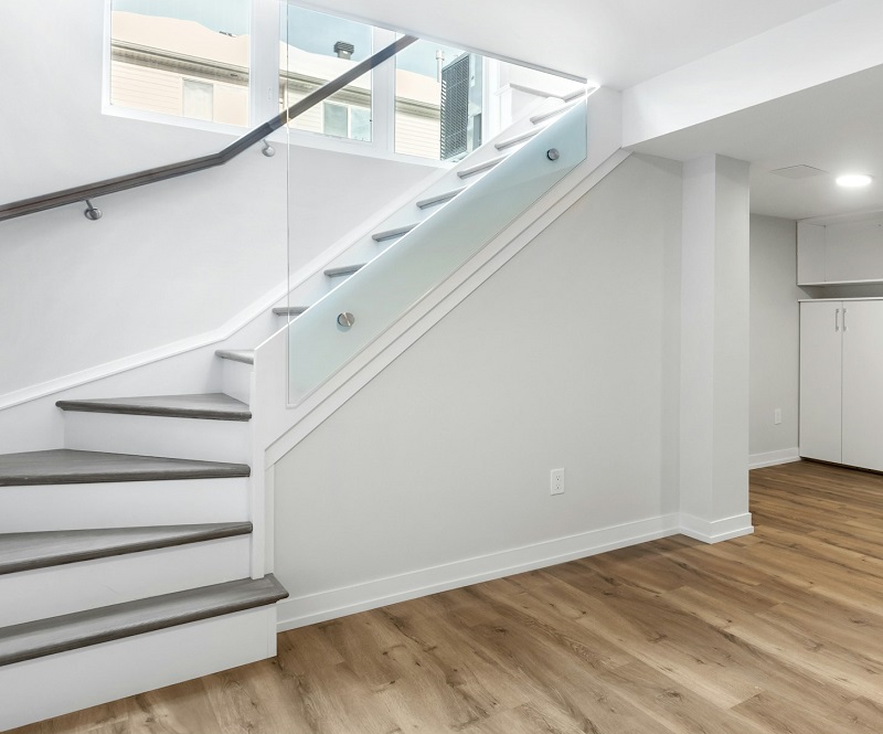 Remodeled basement with basement windows next to modernized staircase