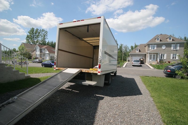 Homeowners getting ready to move from their HOA community: empty moving van in suburban neighborhood